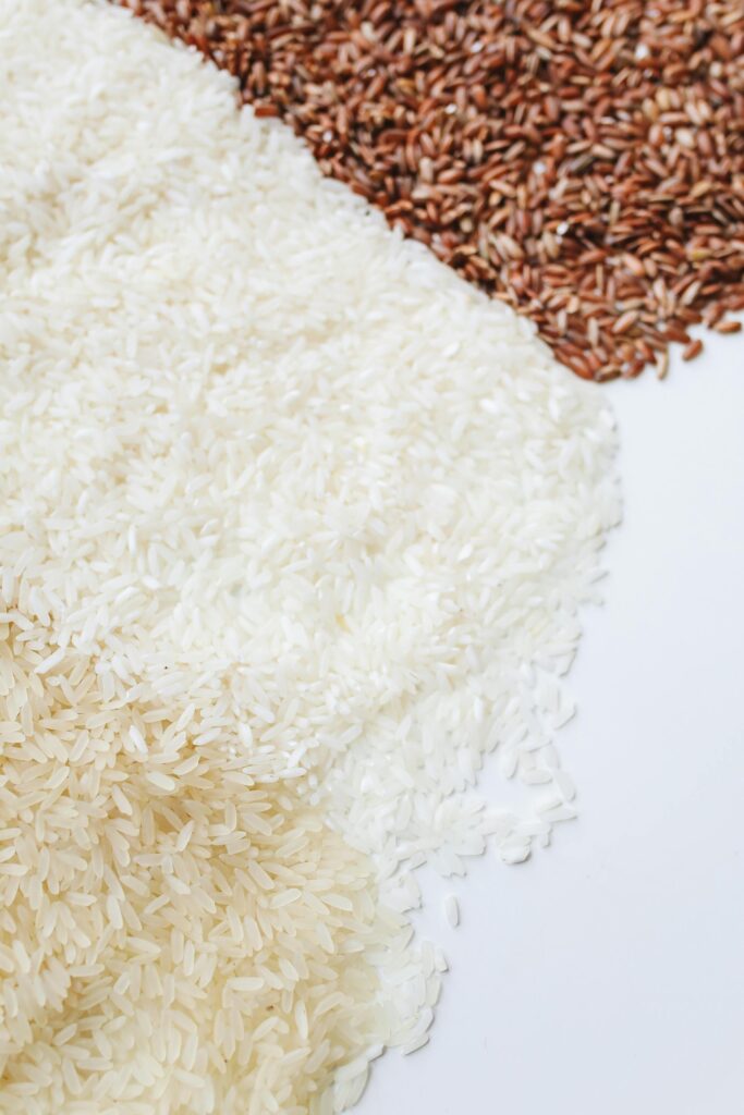 Close-up of assorted uncooked rice demonstrating diversity in grain types on a white background.